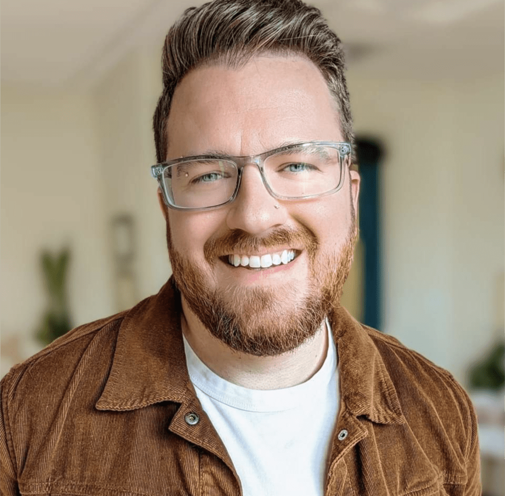 Headshot image of Michael Kuffel. Michael is looking at the camera, wearing glasses and brown jacket over a white shirt.