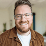 Headshot image of Michael Kuffel. Michael is looking at the camera, wearing glasses and brown jacket over a white shirt.