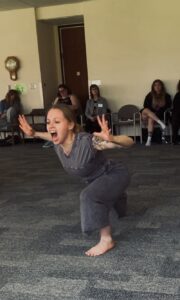 Alicia, a white woman wearing a grey outfit with hair back and tattoos, is dancing during the "share your practice" closing ceremony at the Redefine Therapy Expressive Arts Retreat at The Villa Maria in 2025