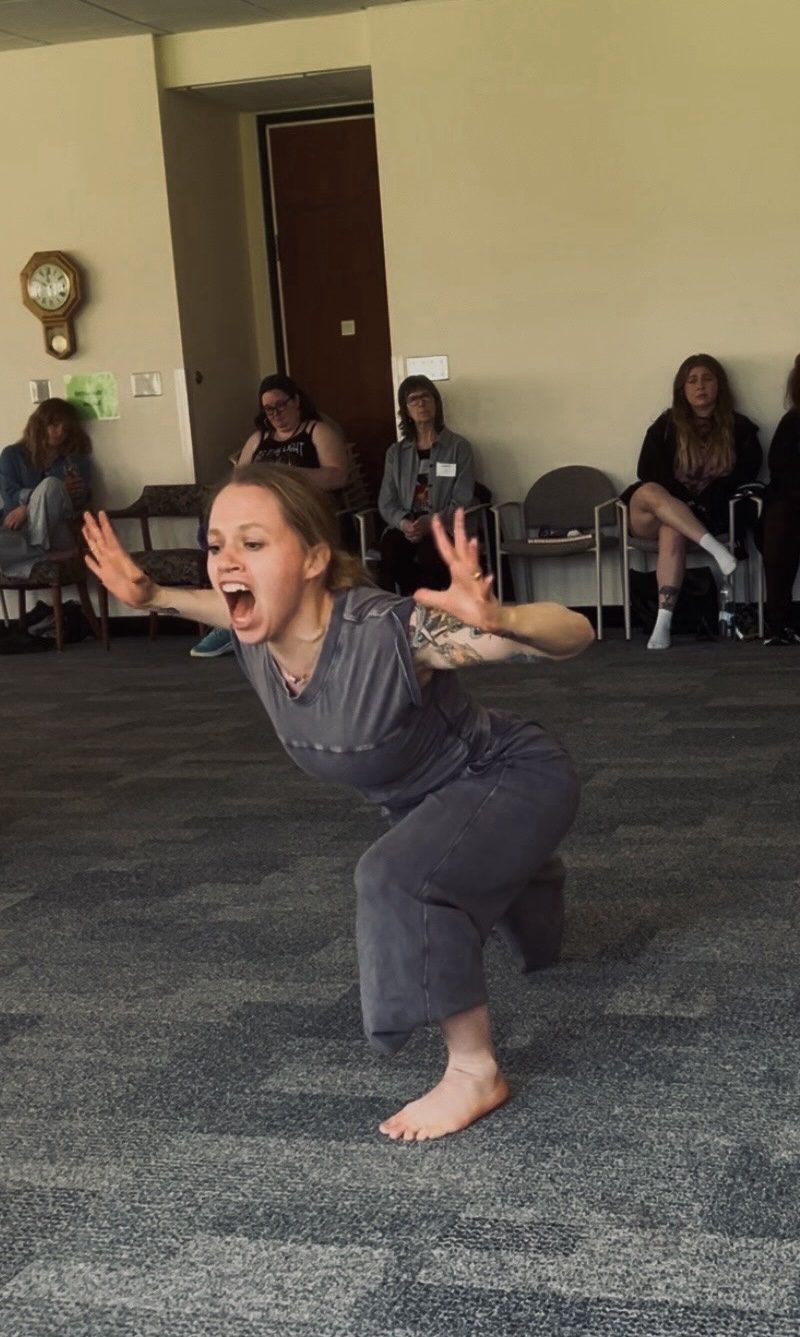 Alicia, a white woman wearing a grey outfit with hair back and tattoos, is dancing during the "share your practice" closing ceremony at the Redefine Therapy Expressive Arts Retreat at The Villa Maria in 2025