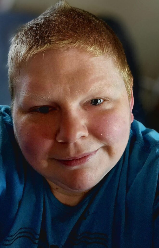 white person with short blonde-red hair looking at camera with blue eyes